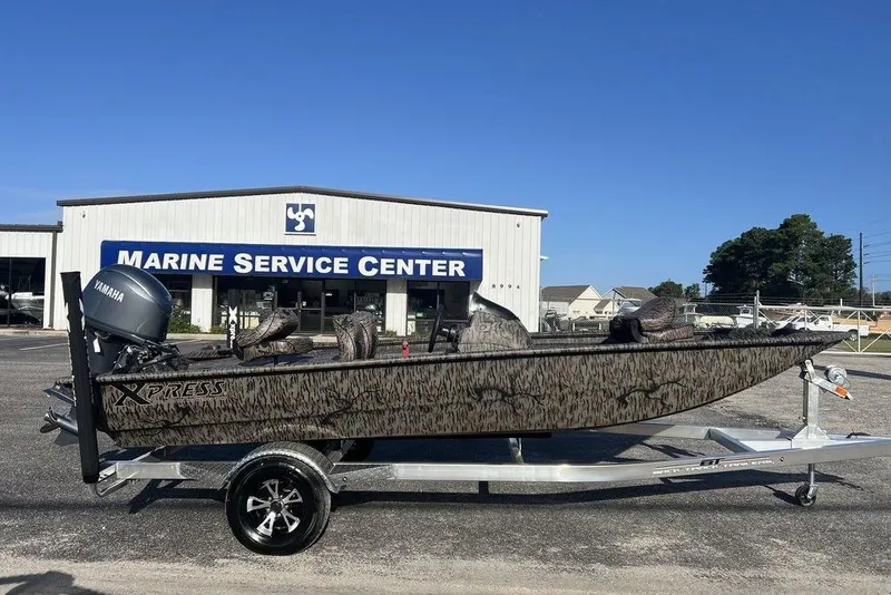 Slide: The Image of 2026 Xpress XP170 boat on trailer, parked roadside under clear sky. - 0