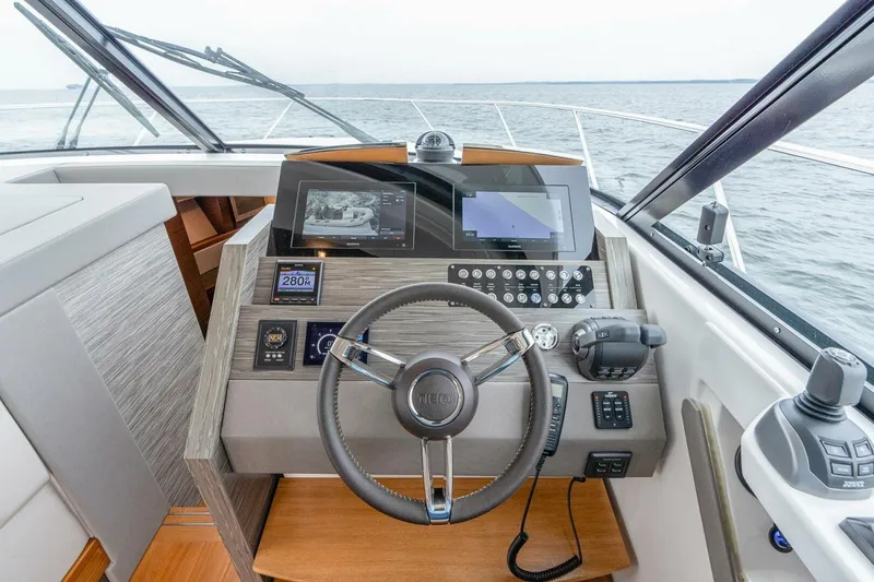 Slide: The Image of 2021 Tiara Yachts F44 Flybridge helm with modern navigation controls and steering wheel. - 23