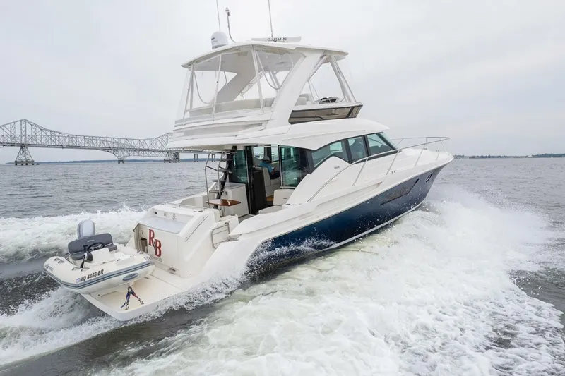 Slide: The Image of 2021 Tiara Yachts F44 Flybridge cruising near a bridge on open water. - 5