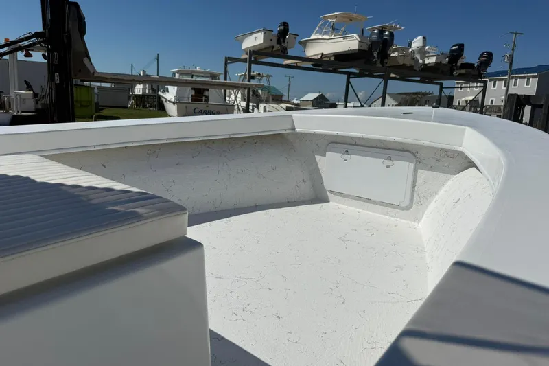Slide: The Image of 2018 C-Hawk 23 Center Console boat interior with seating and storage, docked under clear sky. - 6