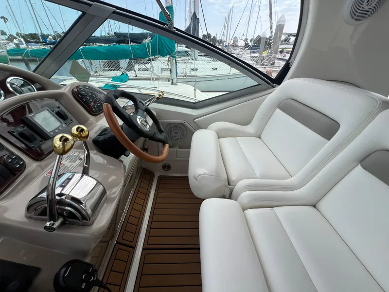 Slide: The Image of 2003 Sea Ray 320 Sundancer helm with white seating and wooden accents. - 13