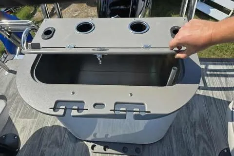 Slide: The Image of 2026 Qwest XRE E-Class boat storage compartment with open lid and hand. - 8