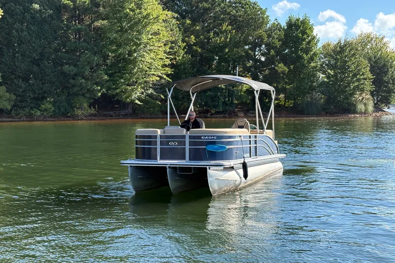 Slide: The Image of 2023 Harris HCX 230 Stern Radius pontoon boat on a serene lake with lush trees. - 11