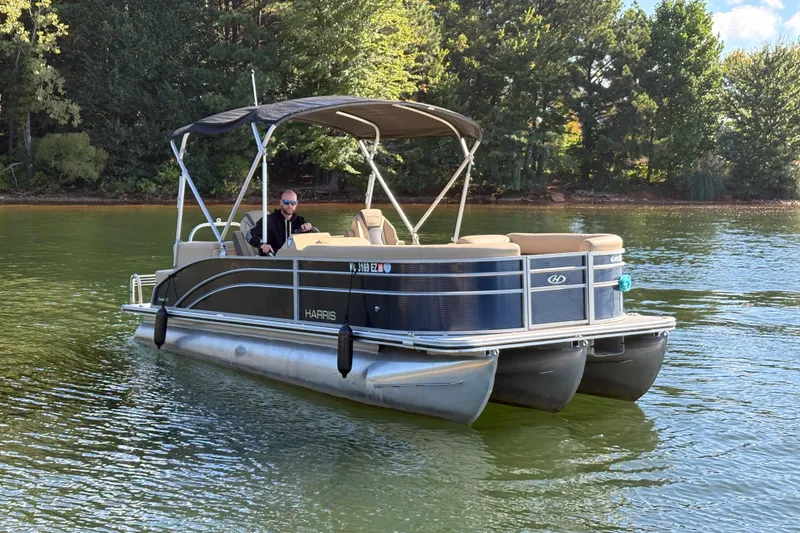 Slide: The Image of 2023 Harris HCX 230 Stern Radius pontoon boat on a serene lake. - 14