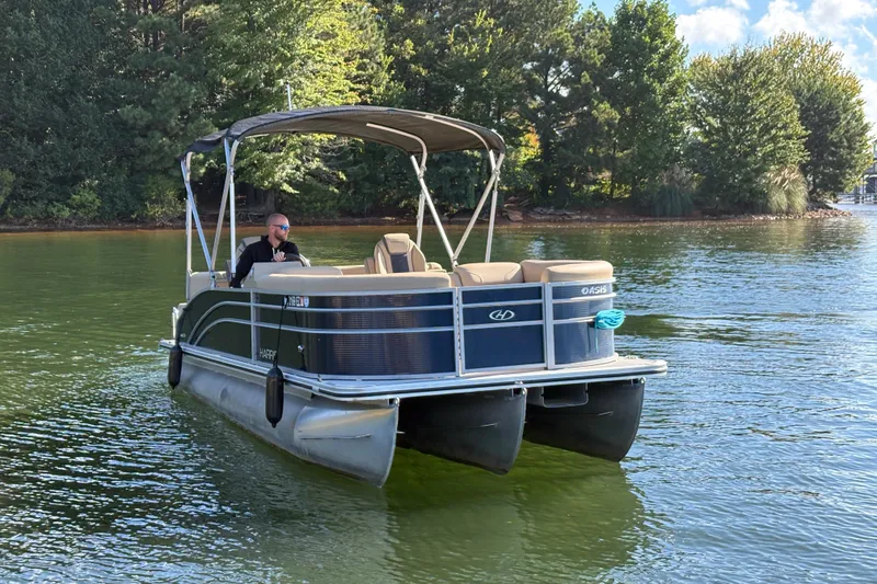 Slide: The Image of 2023 Harris HCX 230 Stern Radius pontoon boat on a lake with a person onboard. - 5