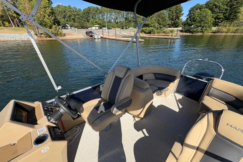 Slide: The Image of 2023 Harris HCX 230 Stern Radius pontoon boat interior with steering wheel and seating. - 7