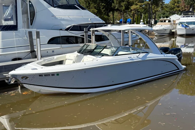 Slide: The Image of 2021 Cobalt 30SC boat docked in a marina, surrounded by other vessels. - 0