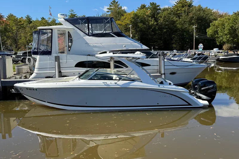 Slide: The Image of 2021 Cobalt 30SC boat docked beside a larger yacht in a marina. - 1