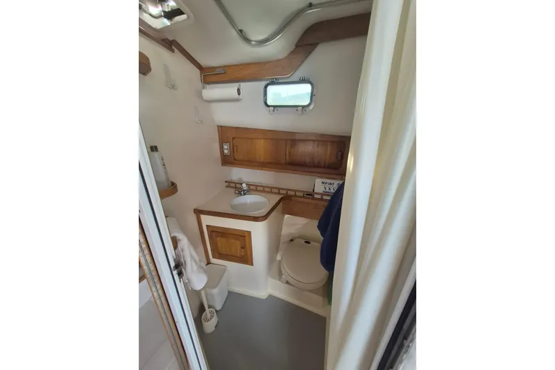 Slide: The Image of Compact bathroom in 1999 Nauset 33 Bridge Deck boat with wooden accents and porthole window. - 11