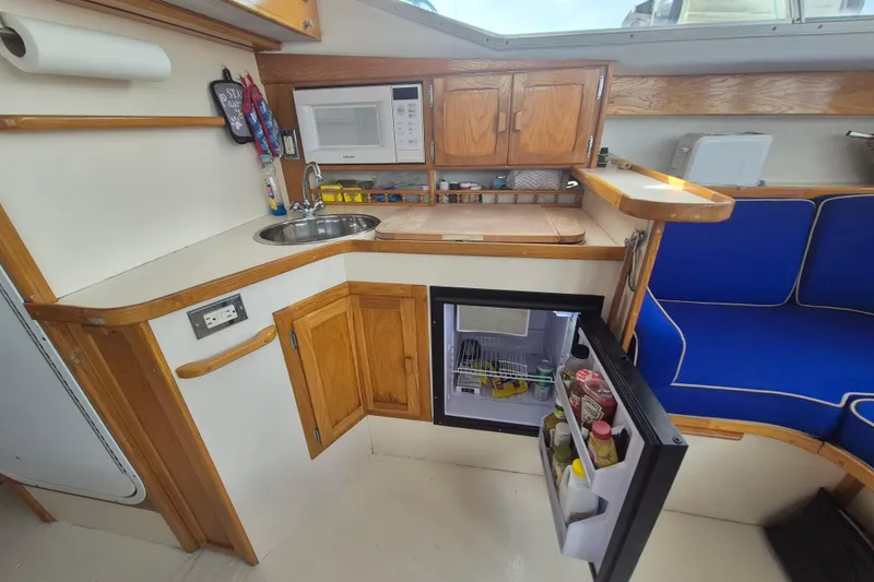 Slide: The Image of Compact kitchen area in a 1999 Nauset 33 Bridge Deck boat with fridge and microwave. - 14
