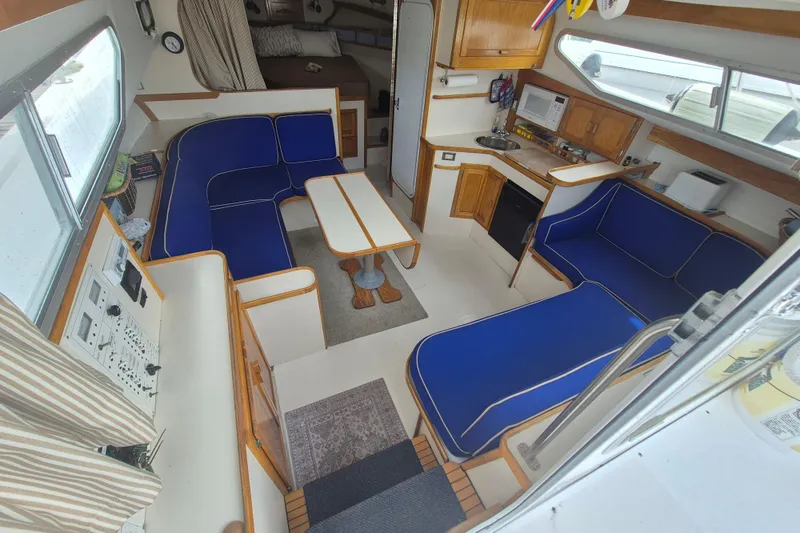 Slide: The Image of Interior of 1999 Nauset 33 Bridge Deck with blue seating, kitchenette, and cozy layout. - 2
