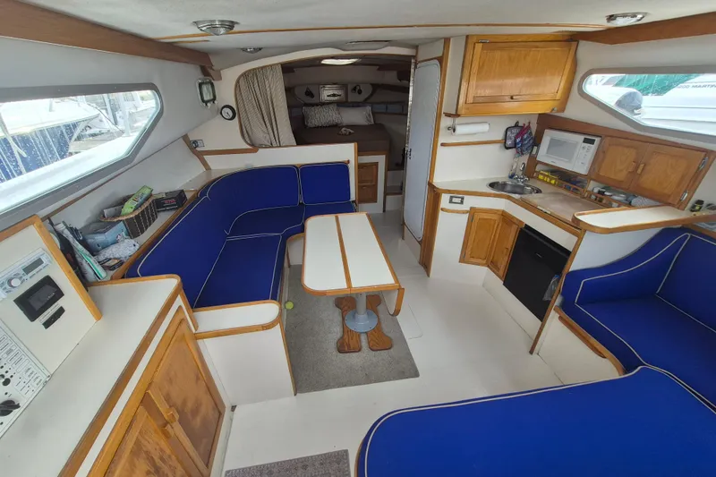 Slide: The Image of Interior of 1999 Nauset 33 Bridge Deck with blue seating, kitchenette, and dining area. - 3
