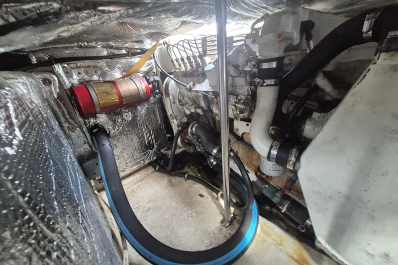 Slide: The Image of Engine room of 1999 Nauset 33 Bridge Deck boat with visible components and fire extinguisher. - 32