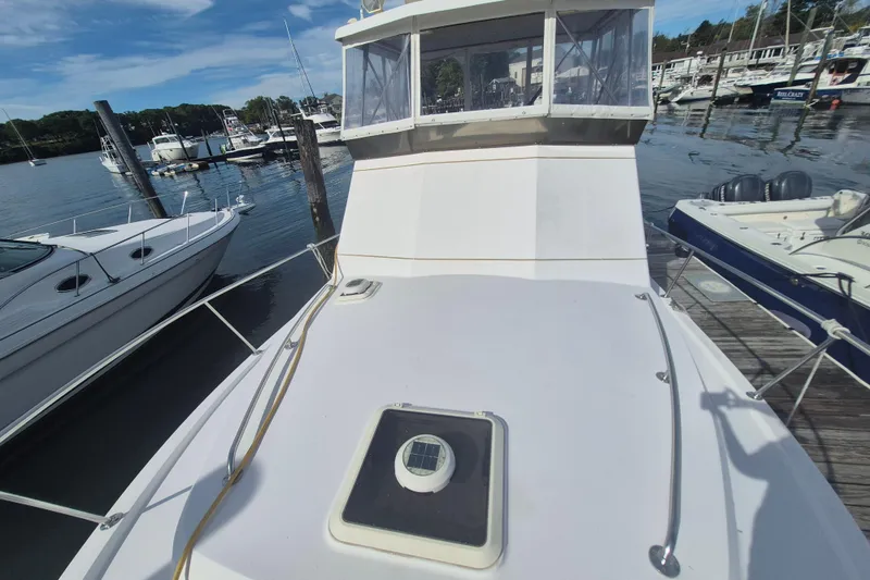 Slide: The Image of 1999 Nauset 33 Bridge Deck boat docked at a marina, surrounded by other vessels. - 49