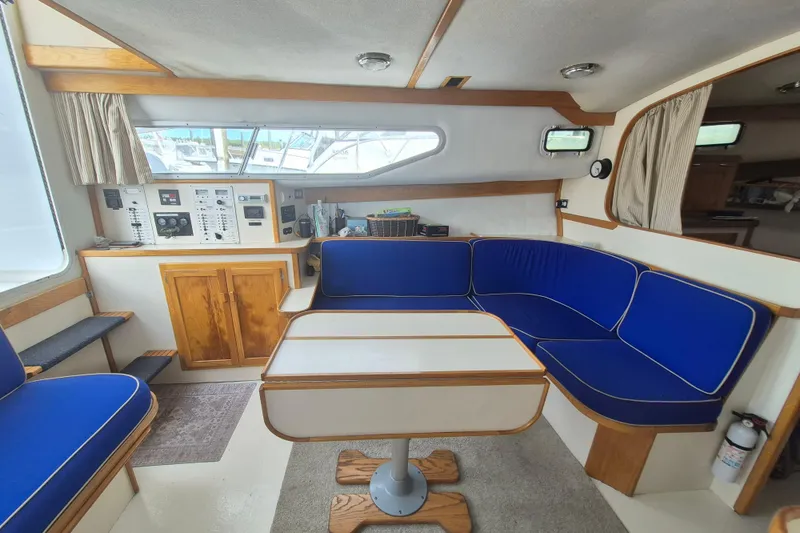 Slide: The Image of Interior of 1999 Nauset 33 Bridge Deck with blue seating and wooden accents. - 5