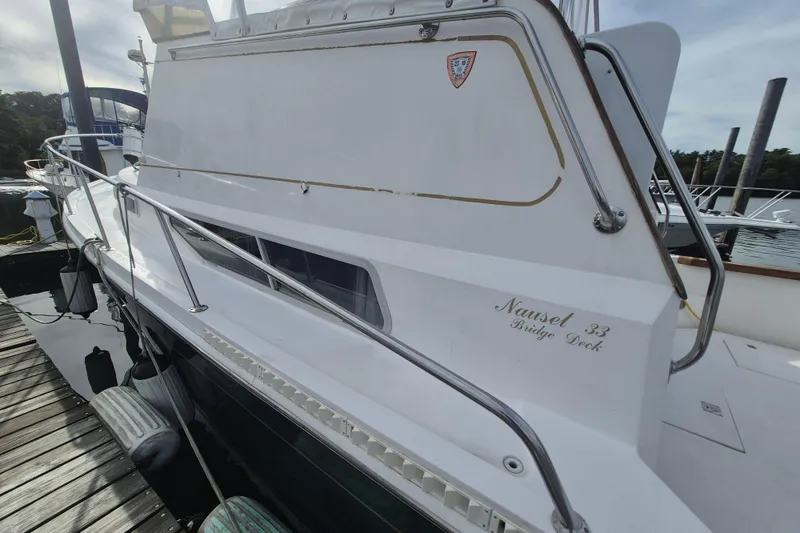 Slide: The Image of 1999 Nauset 33 Bridge Deck boat docked, featuring sleek white design and railing. - 50