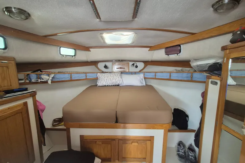 Slide: The Image of Interior cabin of 1999 Nauset 33 Bridge Deck boat with cozy bed and wooden accents. - 9