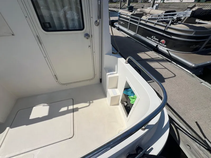 Slide: The Image of 2001 Camano 31 Troll boat deck with railing and docked pontoon in background. - 15