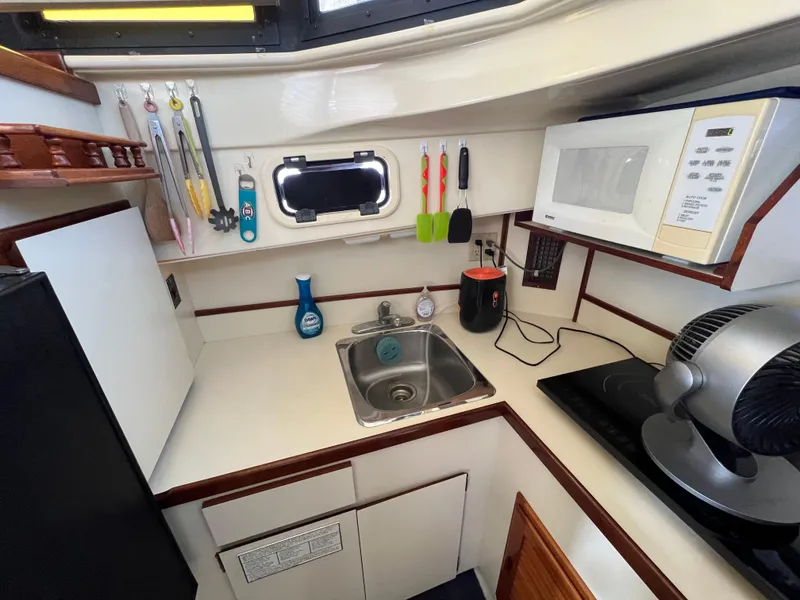 Slide: The Image of Compact kitchen in a 2001 Camano 31 Troll boat with sink, microwave, and utensils. - 49