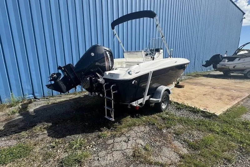 Slide: The Image of 2017 Bayliner Element F18 boat with outboard motor, parked near a blue building. - 4