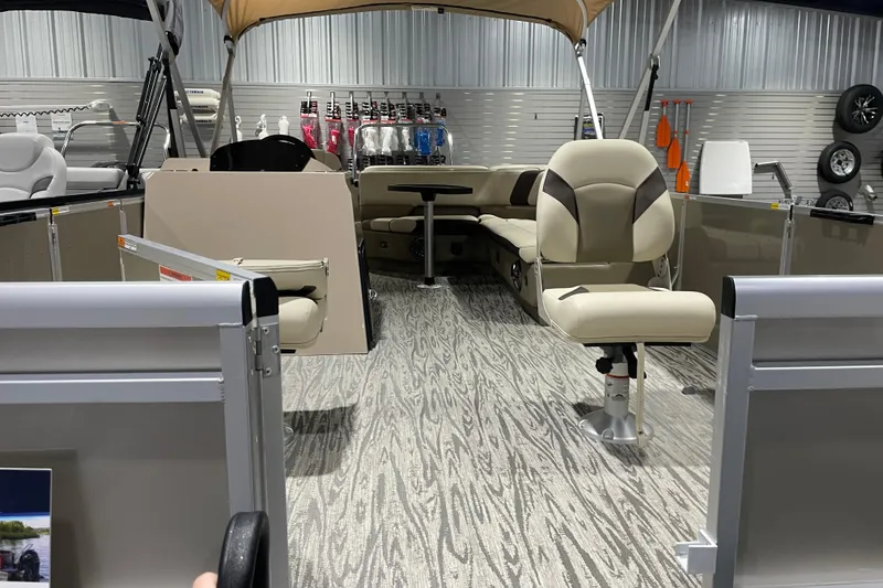 Slide: The Image of 2025 SunCatcher Select 320FC pontoon boat interior with seating and helm, displayed in showroom. - 10