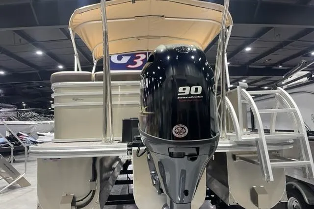 Slide: The Image of 2025 SunCatcher Select 320FC pontoon boat with 90 horsepower engine displayed indoors. - 2