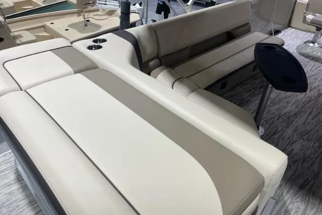 Slide: The Image of 2025 SunCatcher Select 320FC boat interior with beige seating and cup holders. - 8