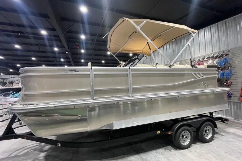 Slide: The Image of 2025 SunCatcher Select 320FC pontoon boat displayed indoors on a trailer. - 9