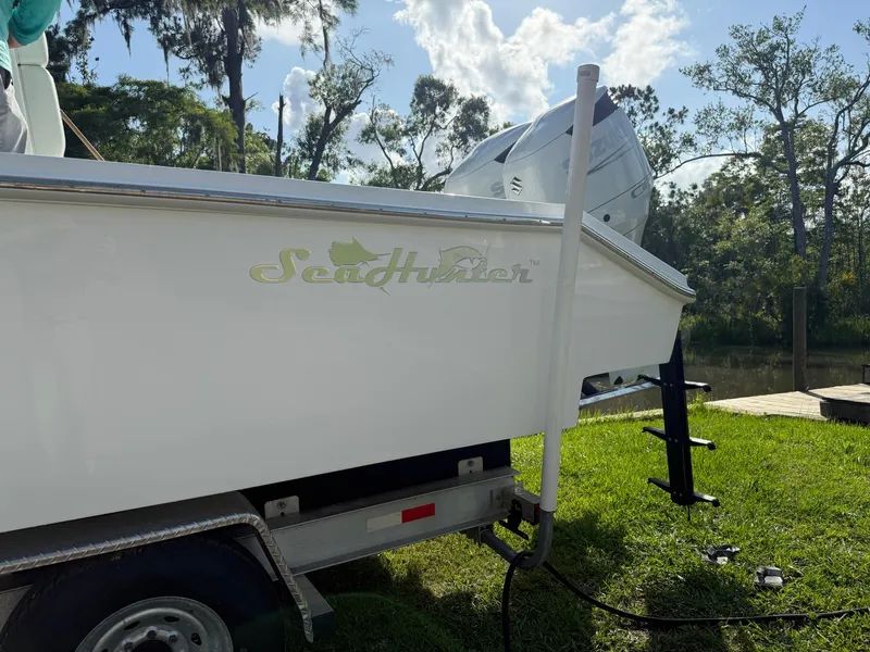 Slide: The Image of 2023 SeaHunter 28 Floridian boat on trailer, parked on grass near water. - 14