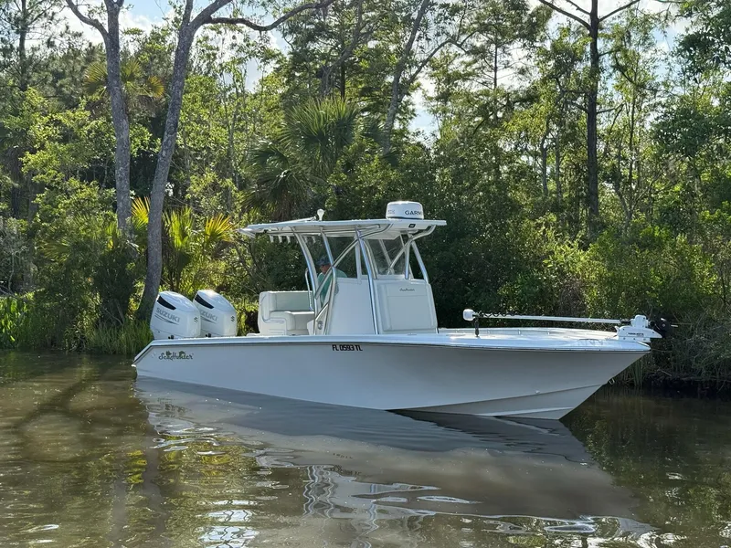 Slide: The Image of 2023 SeaHunter 28 Floridian boat on calm water, surrounded by lush greenery. - 2