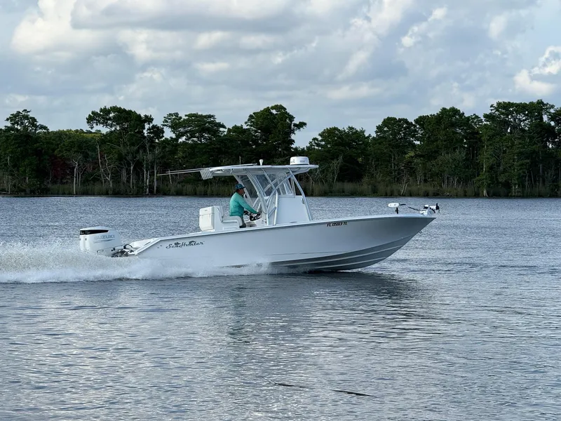Slide: The Image of 2023 SeaHunter 28 Floridian boat cruising on a calm lake with trees in the background. - 4
