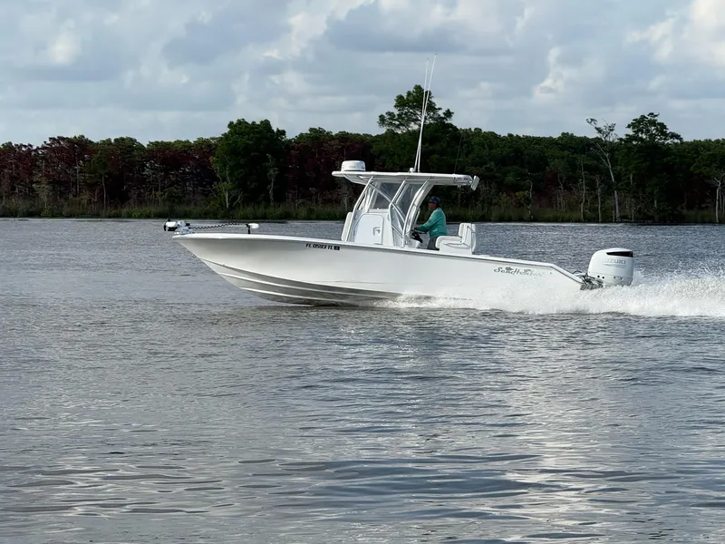 Slide: The Image of 2023 SeaHunter 28 Floridian boat cruising on a calm lake with trees in the background. - 5
