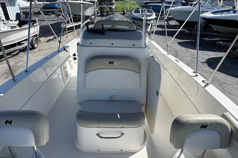 Slide: The Image of 2015 NauticStar 231 Angler boat interior with seating and console, docked among other boats. - 14