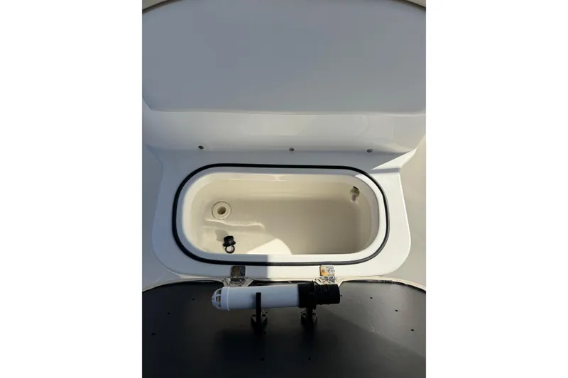 Slide: The Image of 2015 NauticStar 231 Angler boat compartment, open and empty, with visible drain plug. - 22