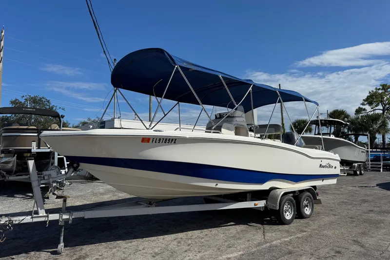 Slide: The Image of 2015 NauticStar 231 Angler boat on trailer with blue canopy, parked outdoors. - 3