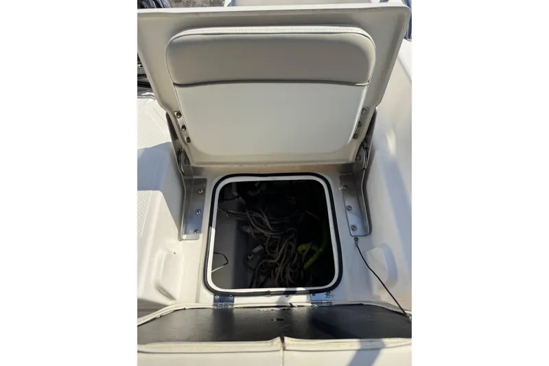 Slide: The Image of 2015 NauticStar 231 Angler boat storage compartment with open lid and ropes inside. - 31