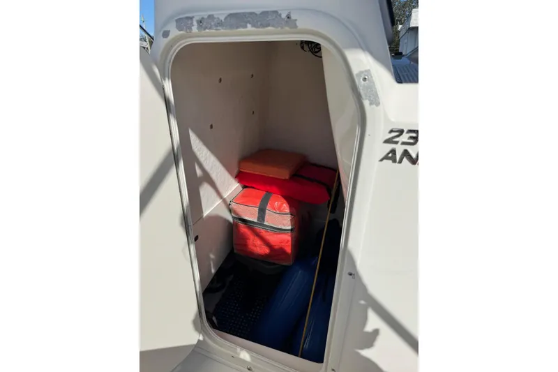 Slide: The Image of 2015 NauticStar 231 Angler storage compartment with life jackets and gear. - 32