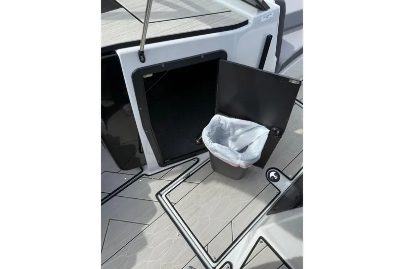 Slide: The Image of 2024 Yamaha Boats 222XD interior with open storage compartment and trash bin. - 14