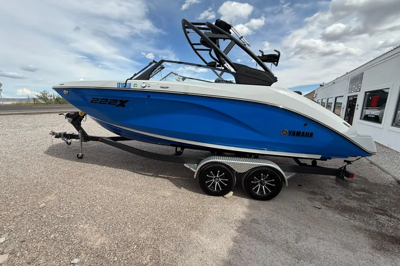 Slide: The Image of 2024 Yamaha Boats 222XD in blue, parked on a trailer under a cloudy sky. - 4