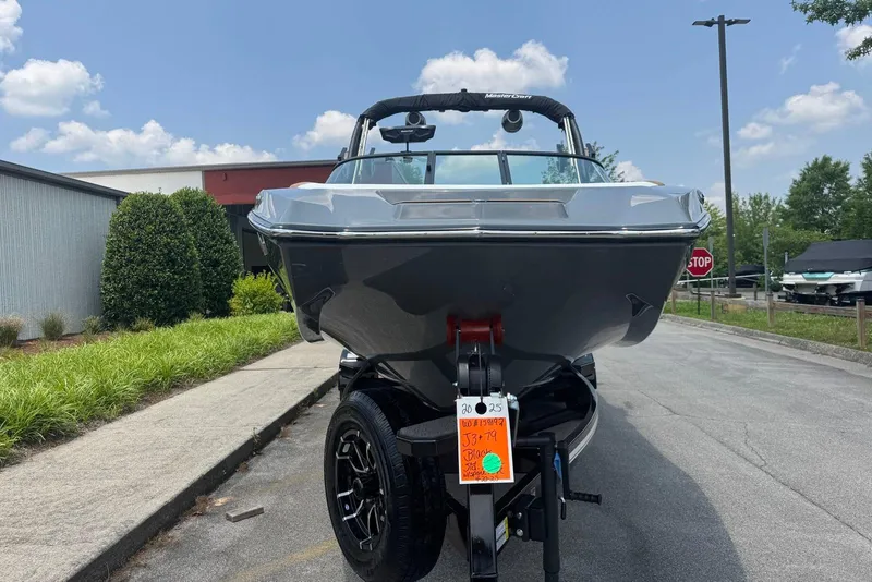 Slide: The Image of 2025 MasterCraft NXT24 boat on trailer, parked outdoors under a clear sky. - 5