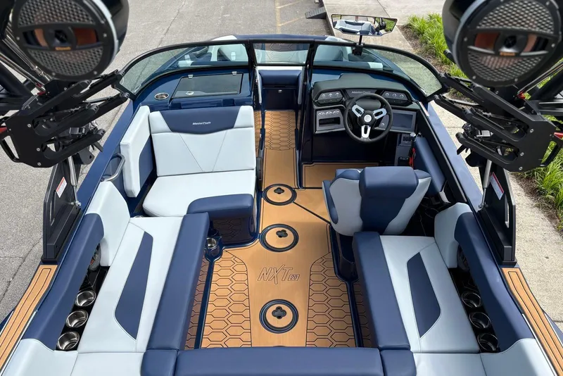 Slide: The Image of 2025 MasterCraft NXT20 boat interior with blue and white seating, modern dashboard, and stylish flooring. - 12