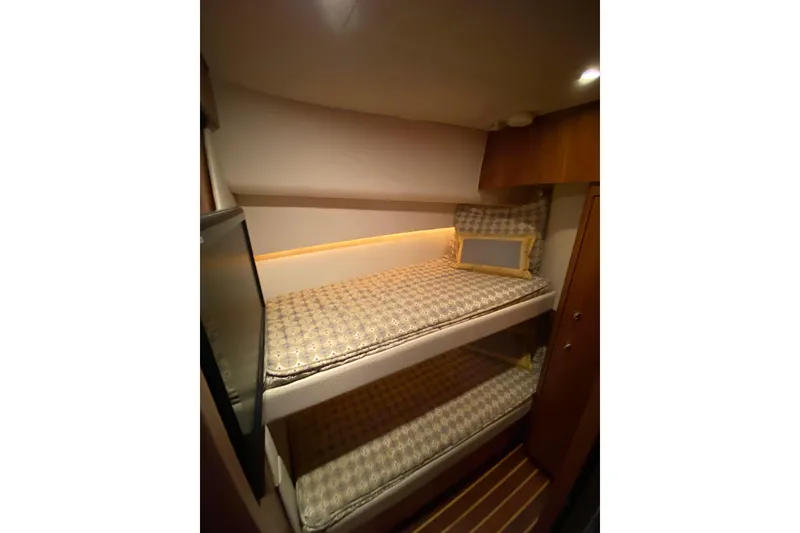 Slide: The Image of Bunk beds in 2012 Tiara Yachts 4800 Convertible cabin, featuring cozy lighting and patterned bedding. - 15