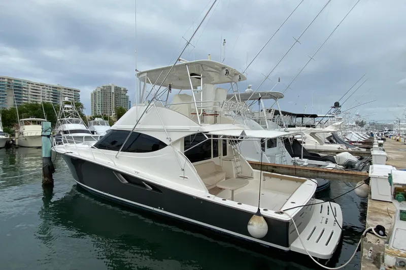 Slide: The Image of 2012 Tiara Yachts 4800 Convertible docked at marina, surrounded by other boats. - 2