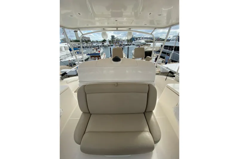 Slide: The Image of 2012 Tiara Yachts 4800 Convertible interior with beige seating at marina. - 5