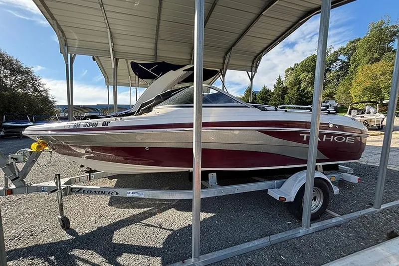 The Image of 2009 Tahoe Q5i Sport boat on trailer under metal canopy. - 0