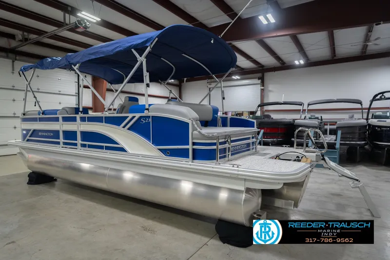 Slide: The Image of 2026 Bennington 23 SSB pontoon boat with blue canopy in indoor showroom. - 10