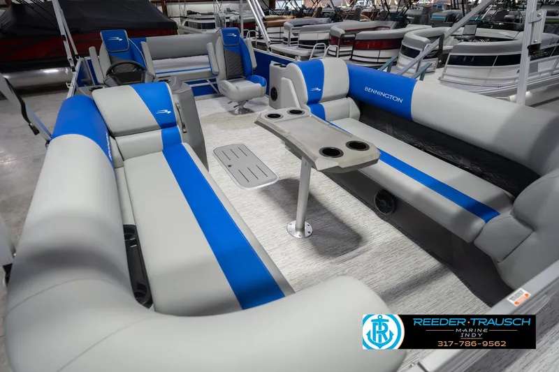 Slide: The Image of 2026 Bennington 23 SSB pontoon boat interior with blue and gray seating, cup holders, and table. - 13