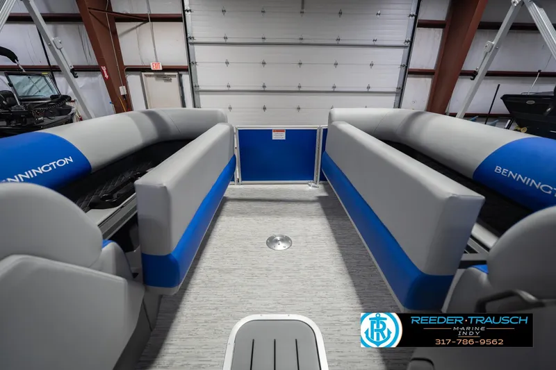 Slide: The Image of 2026 Bennington 23 SSB pontoon boat interior with blue and gray seating in a showroom. - 23