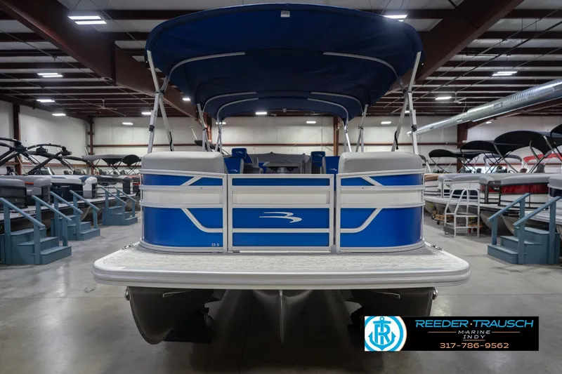 Slide: The Image of 2026 Bennington 23 SSB pontoon boat in showroom, featuring blue and white design. - 5