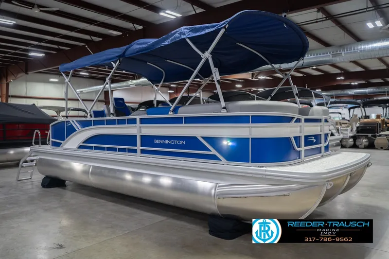Slide: The Image of 2026 Bennington 23 SSB pontoon boat with blue canopy in showroom. - 6